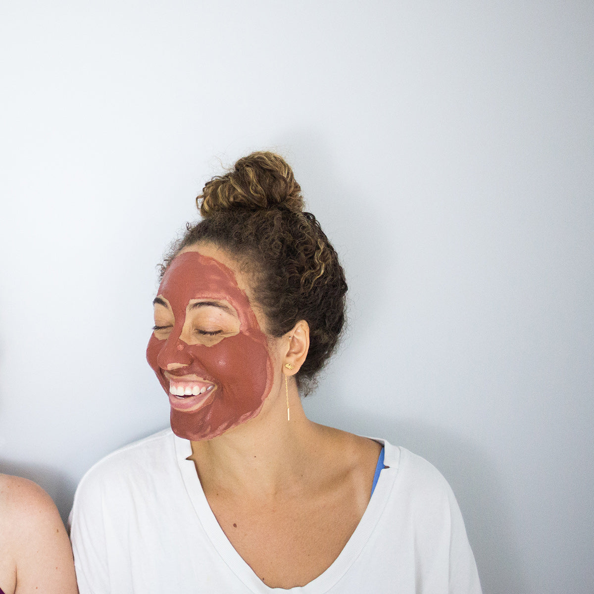 Laughing woman using rose face mask treatment