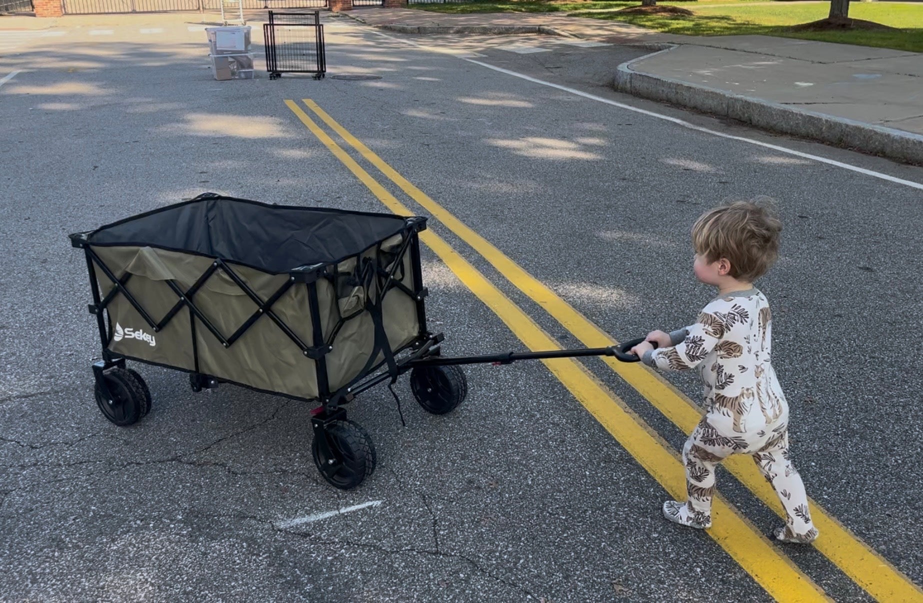 Child pulling a folding wagon on a paved road